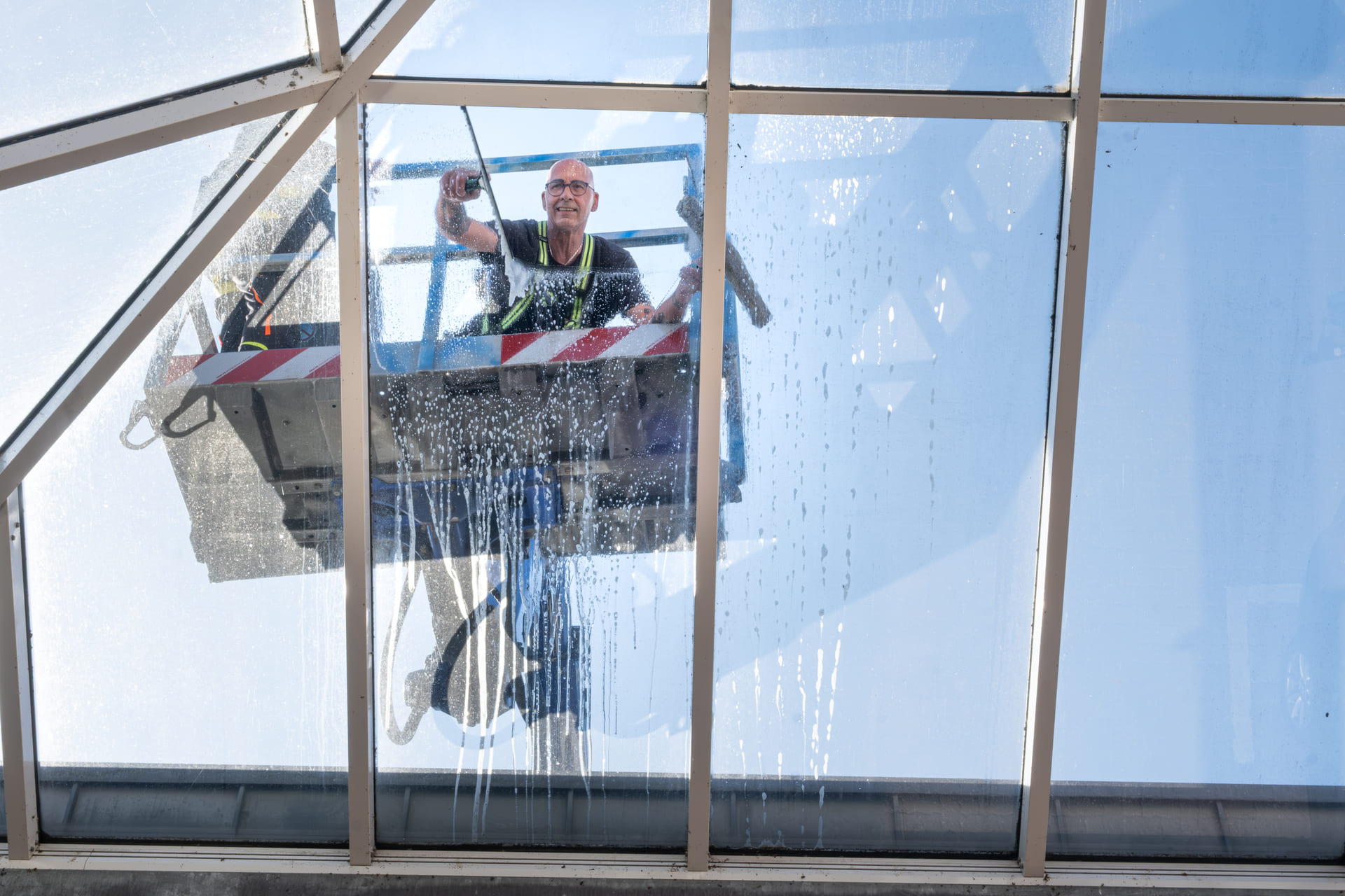 Ein Mitarbeiter von VDW steht auf einem Lift und putzt Fenster